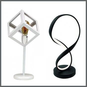 Φωτογραφία δύο μοντέρνων και μίνιμαλ επιτραπέζιων φωτιστικών. Το ένα με λευκό μεταλλικό κύβο και λάμπα και το άλλο μαύρο με λεντοταινία στο σχήμα του 8.